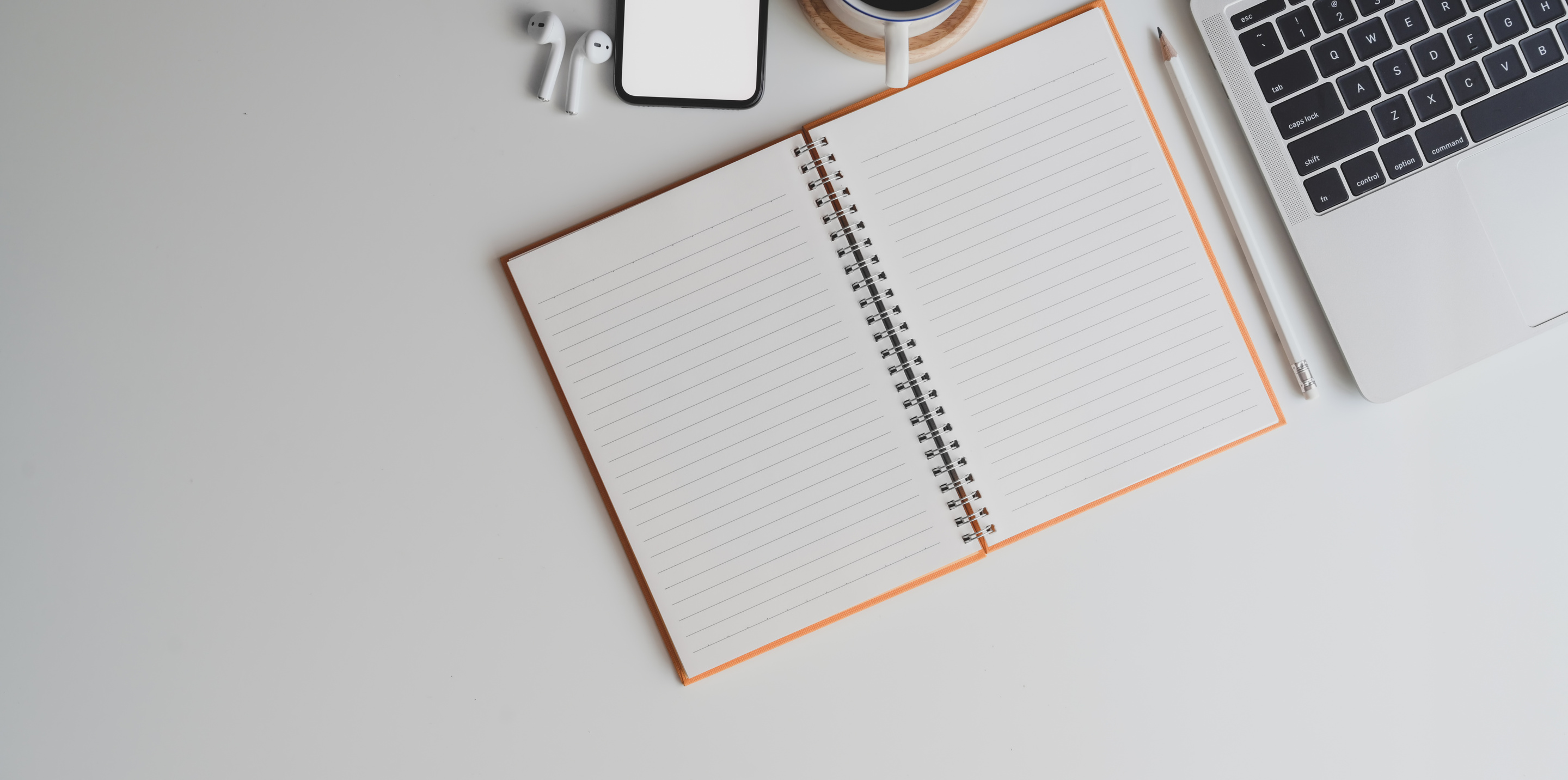 Notepad with laptop on white desk